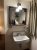 Bathroom sink and mirror area in a lodge room at Yellowstone National Park, with a small shelf and toiletries visible by the sink.