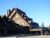 Rustic multi-gabled lodge at Yellowstone National Park near Old Faithful, built in dark wood with flags atop.