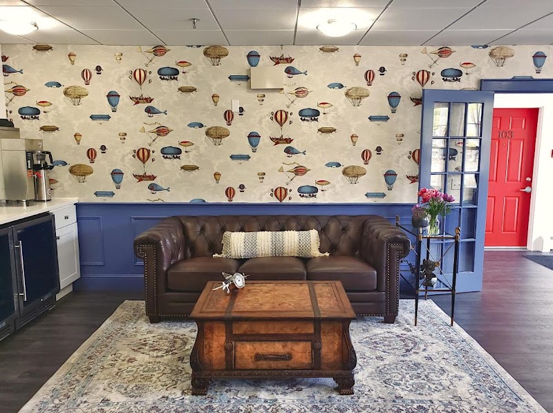 Cozy living room in Acadia National Park style with a brown leather sofa, wooden coffee table, blue wainscoting, and balloon wallpaper.
