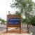 Brown wooden sign on a dirt patch beside a road, blue panels advertise a bakery and bistro near Arches National Park.