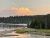 Yellowstone Lake shoreline at sunset with a pine forest along the rocky banks in Yellowstone National Park