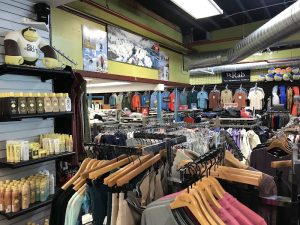 Inside a busy gift shop at Acadia National Park, clothing racks with jackets and hats and sunscreen.