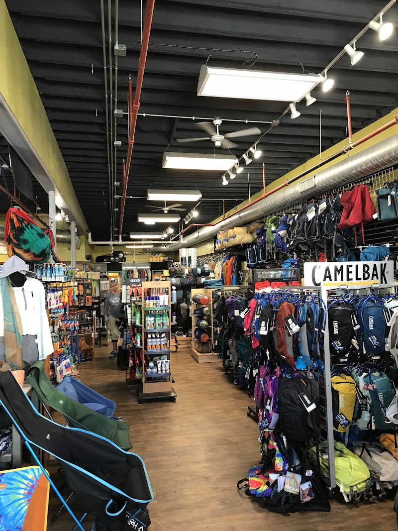 Bright indoor gear shop filled with colorful backpacks, jackets, camping chairs, and hiking gear in Acadia National Park.