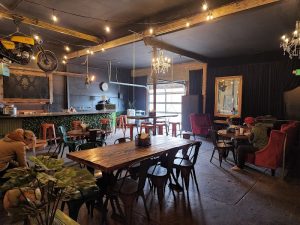 Industrial dining area in Arches National Park with a long wooden table, metal chairs, and string lights.
