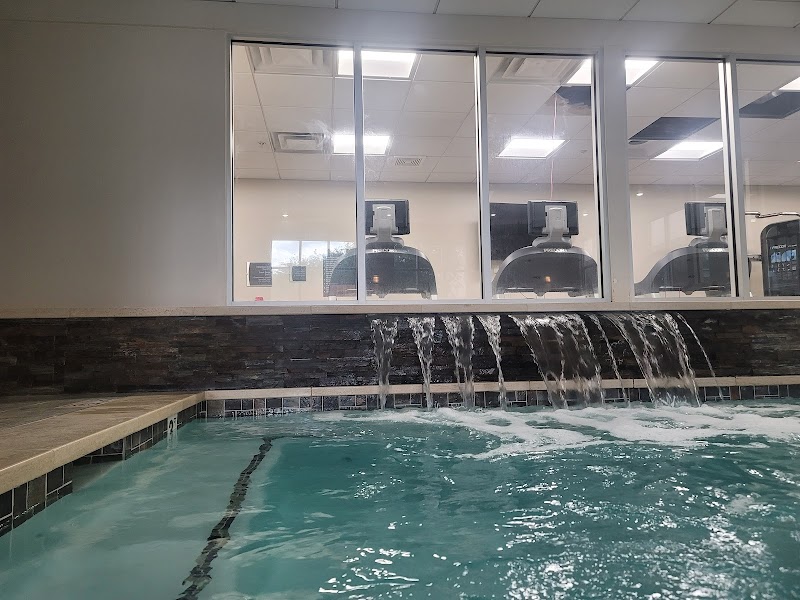 Indoor pool with turquoise water and cascading spouts, seen through glass walls from the gym in Arches National Park.