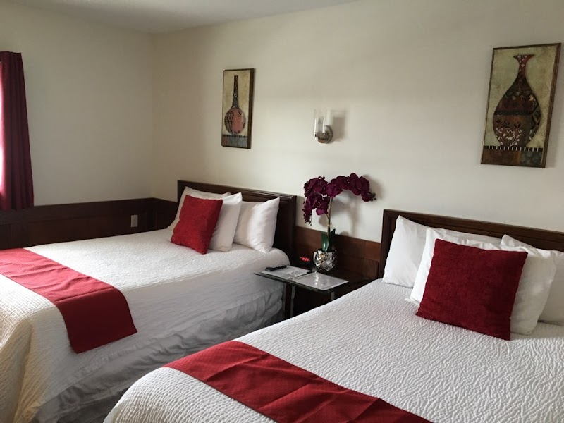 Cozy guest room with two double beds and red accents at Atlantic Coast Inn in Acadia National Park.