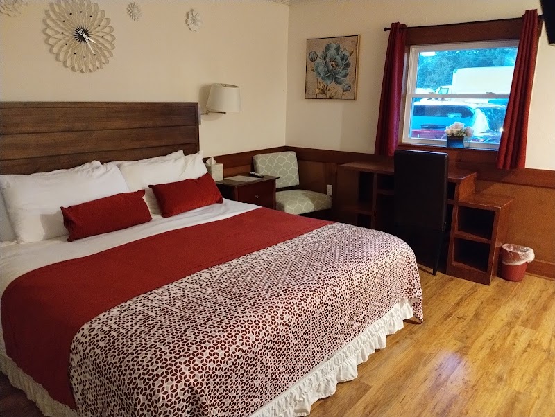 Cozy guest room in a lodge-style hotel within Acadia National Park, featuring a king bed, red accents, and a work desk.