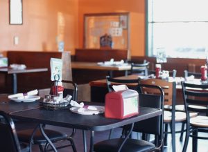Cozy dining room with black metal tables, red napkin holders and condiments, booths along orange walls in Acadia National Park.