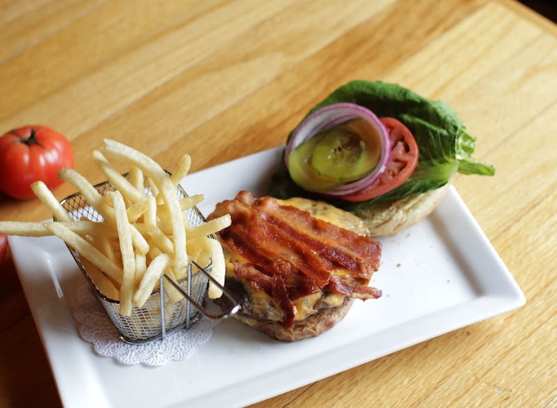 Bacon cheeseburger with fries and greens on a white plate in Bar Harbor, Acadia National Park.