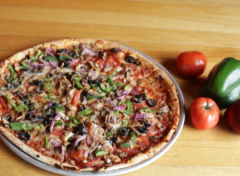 Pizza with peppers, onions and olives on a wooden table near Bar Harbor, Acadia National Park