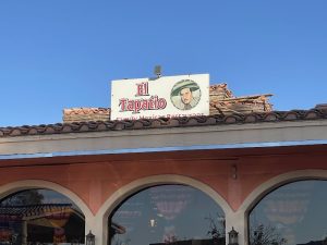Arched-window restaurant with terracotta roof tiles and a Mexican eatery sign under a clear blue sky in Arches National Park.