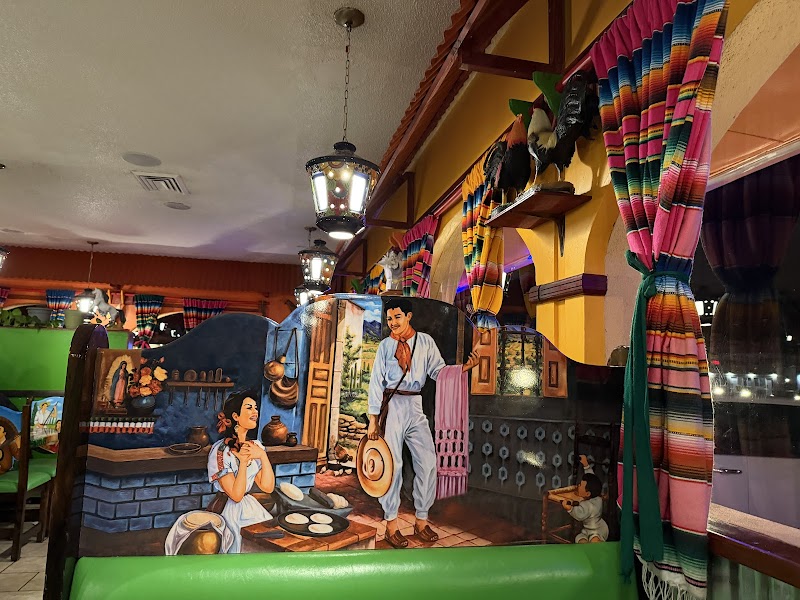 Interior of a colorful Arches National Park themed restaurant with a mural of a couple cooking, striped curtains, and hanging lanterns.