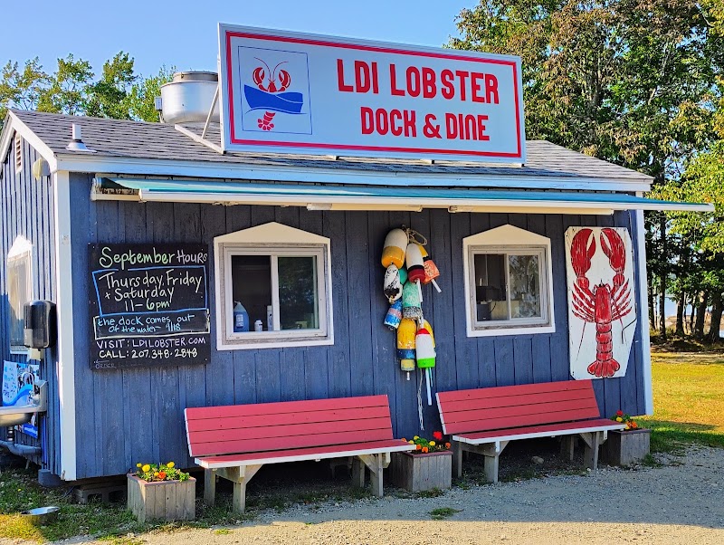 Lobster dock storefront with bright sign, buoys, and red benches in Acadia National Park.