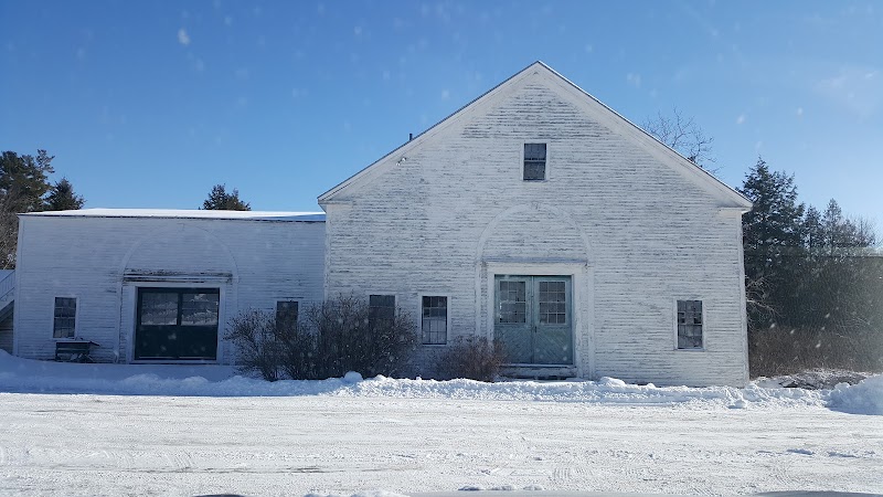 Black House Museum at Woodlawn in Acadia National Park stands white and weathered against a snowy landscape.