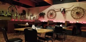 Cozy western dining area with wooden tables, black chairs, wagon wheels, a bull skull on the wall in Badlands National Park.
