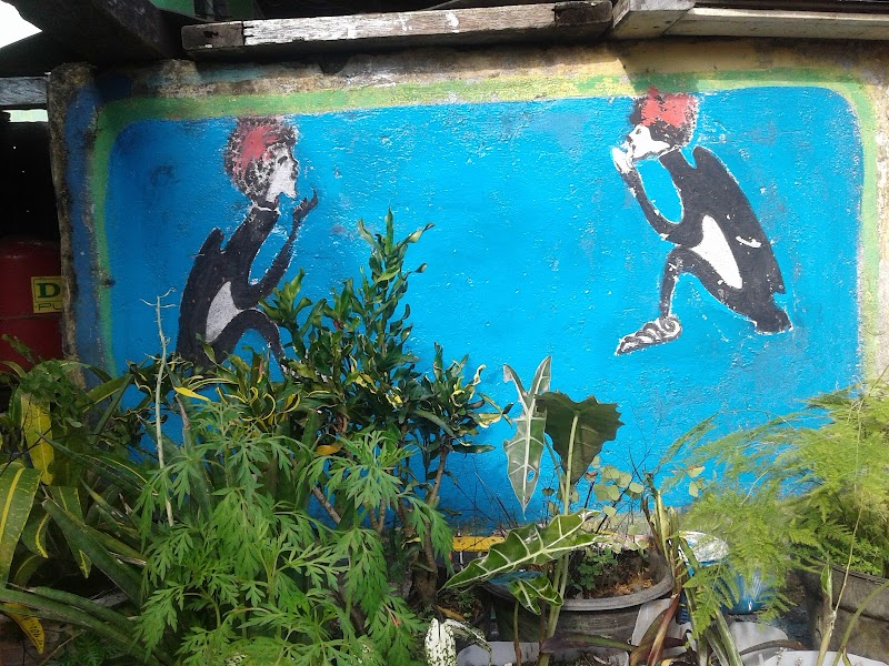 Bright blue mural of two kneeling figures facing each other, with potted plants in the foreground at Badlands National Park.