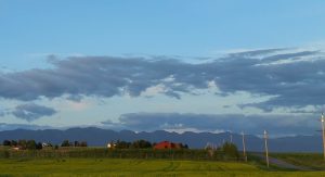 Farmstead scene near Polebridge in Glacier National Park with green fields and distant mountains.
