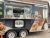 Falafel food trailer with open window, menu boards, and colorful food photos on Yellowstone National Park grounds.