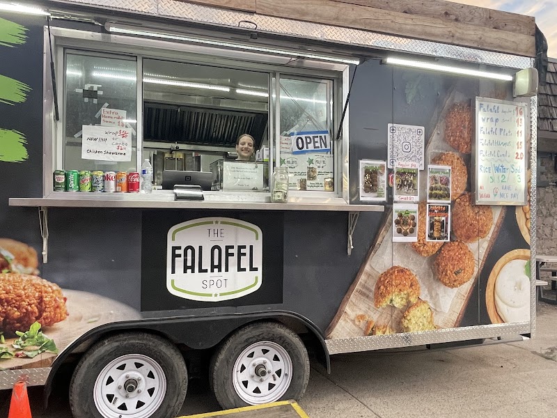 Falafel food trailer with open window, menu boards, and colorful food photos on Yellowstone National Park grounds.