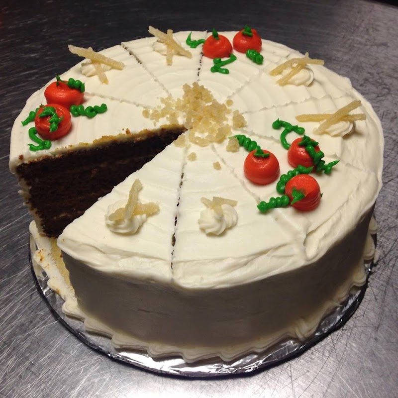 Decorated white-frosted cake served at a Slice of Eden in Acadia National Park, with cherry toppers and green icing accents.