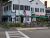Exterior view of a white two-story building with green awnings and outdoor seating, near Acadia National Park.
