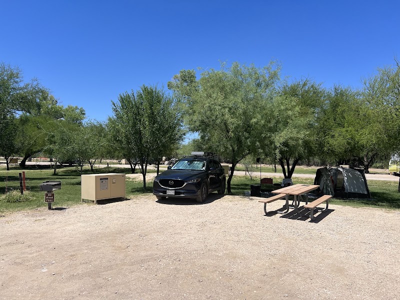 Cottonwood Campground at Big Bend National Park features a shaded site with a tent, a parked SUV, and picnic tables.