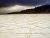 Cracked white salt flats of Badwater Basin stretch toward distant mountains in Death Valley National Park.
