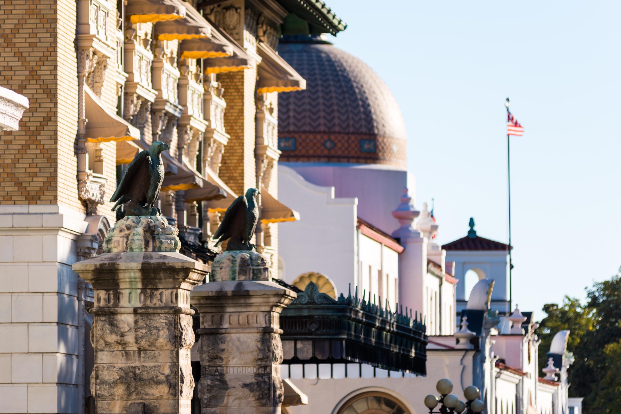 Sculpted eagle pedestals line Bathhouse Row in Hot Springs National Park, with ornate brick facades and a domed bathhouse in the background.