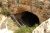 Visitors descend a stone stair path into the Natural Entrance of Carlsbad Caverns National Park, entering a dark cavern chamber.