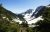 Cascade Pass area in North Cascades National Park shows a snowy alpine valley with jagged peaks and evergreen slopes under a clear blue sky.