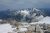 High alpine panorama over rugged granite and snow toward a turquoise lake in North Cascades National Park from a rocky viewpoint.