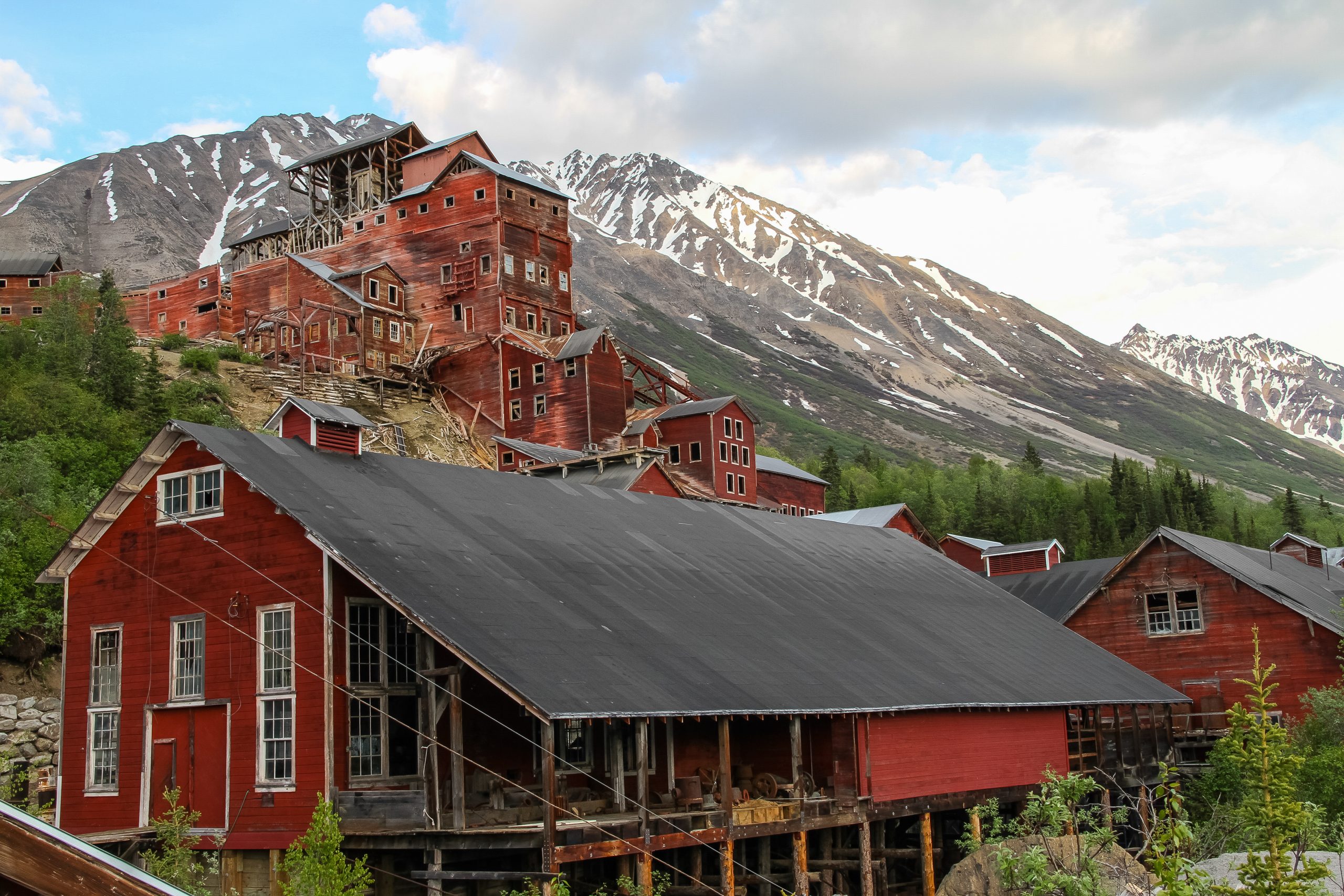 Kennecott Mine and Mill Town in Wrangell - St Elias National Park & Preserve with red buildings against snowy peaks.