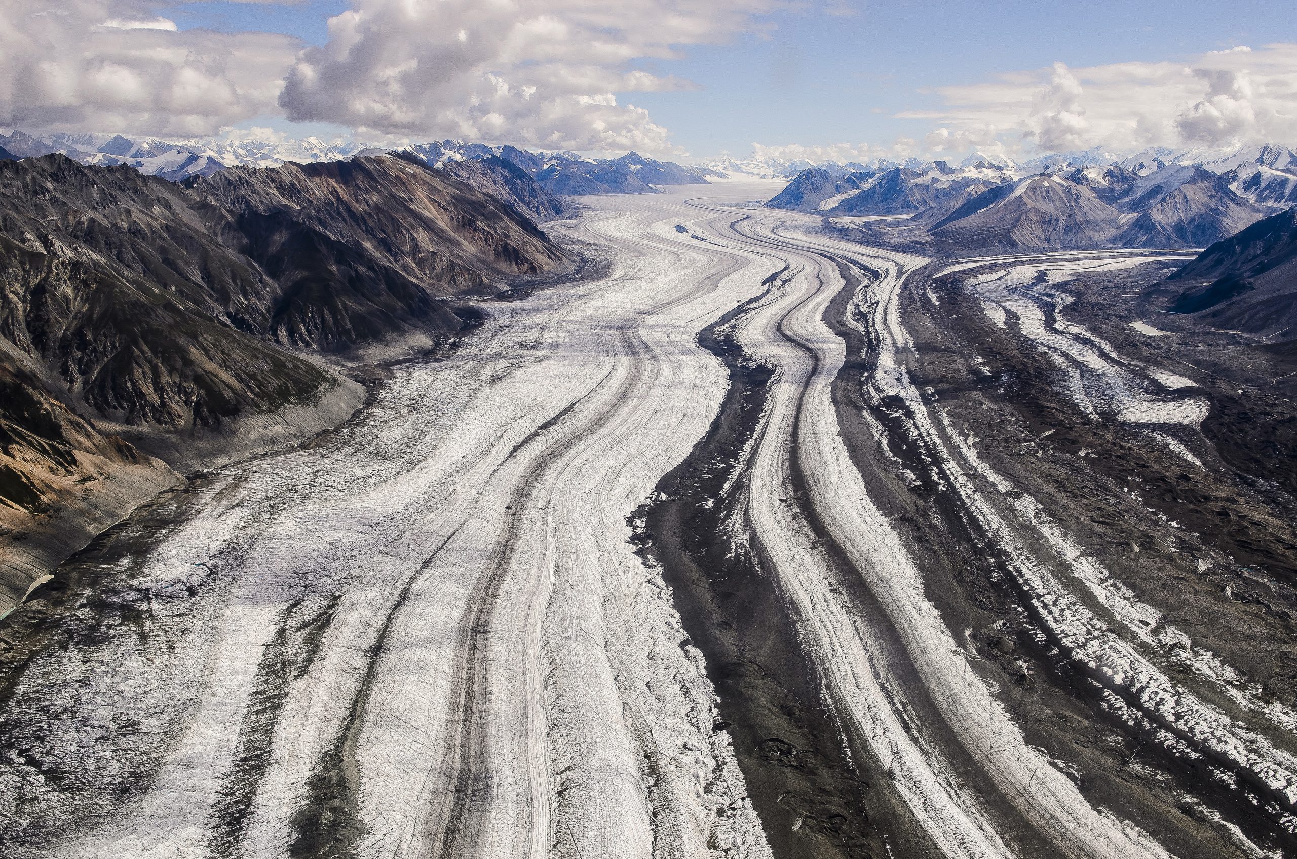Root Glacier winds through Wrangell - St Elias National Park & Preserve’s rugged mountains, revealing braided ice and dark moraines.