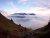 Hikers rest on a rocky slope as a sea of clouds curls around snow-capped Mount Olympus in Olympic National Park.