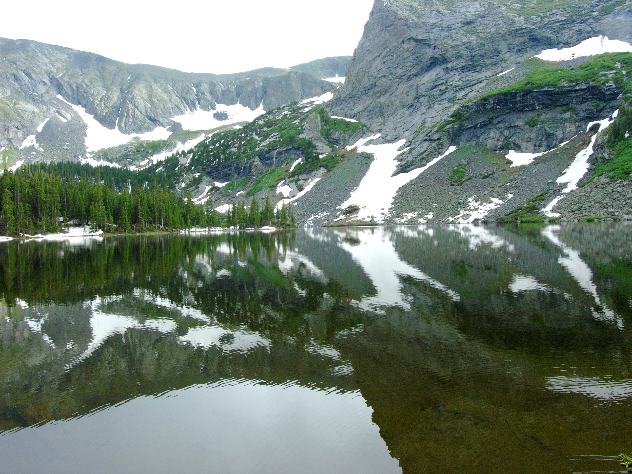 Emerald alpine lake mirrors snow-dusted peaks in the Sangre de Cristo range, Great Sand Dunes National Park & Preserve.