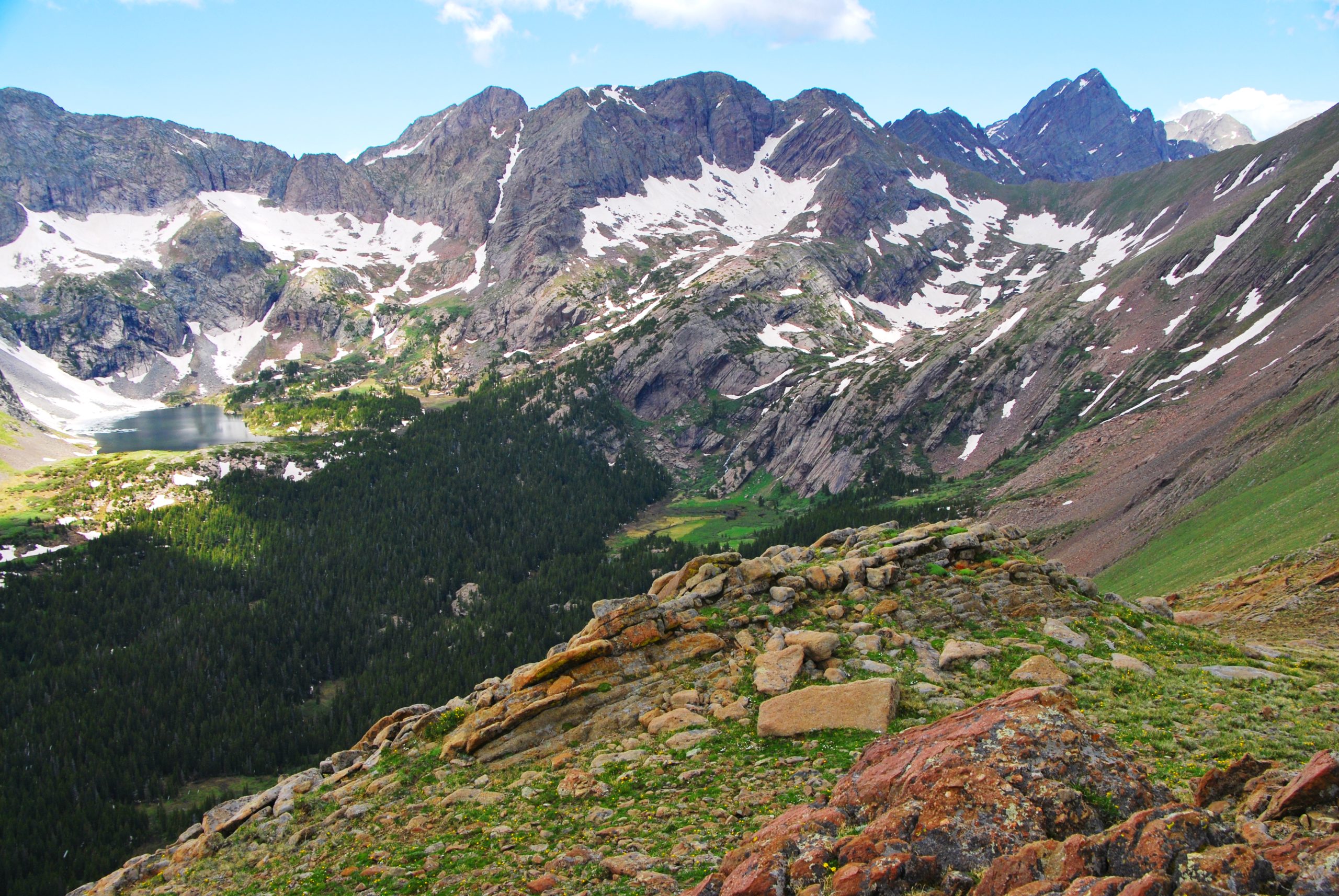 Medano Lake sits in a jagged alpine bowl with snow patches and rocky slopes in Great Sand Dunes National Park & Preserve.