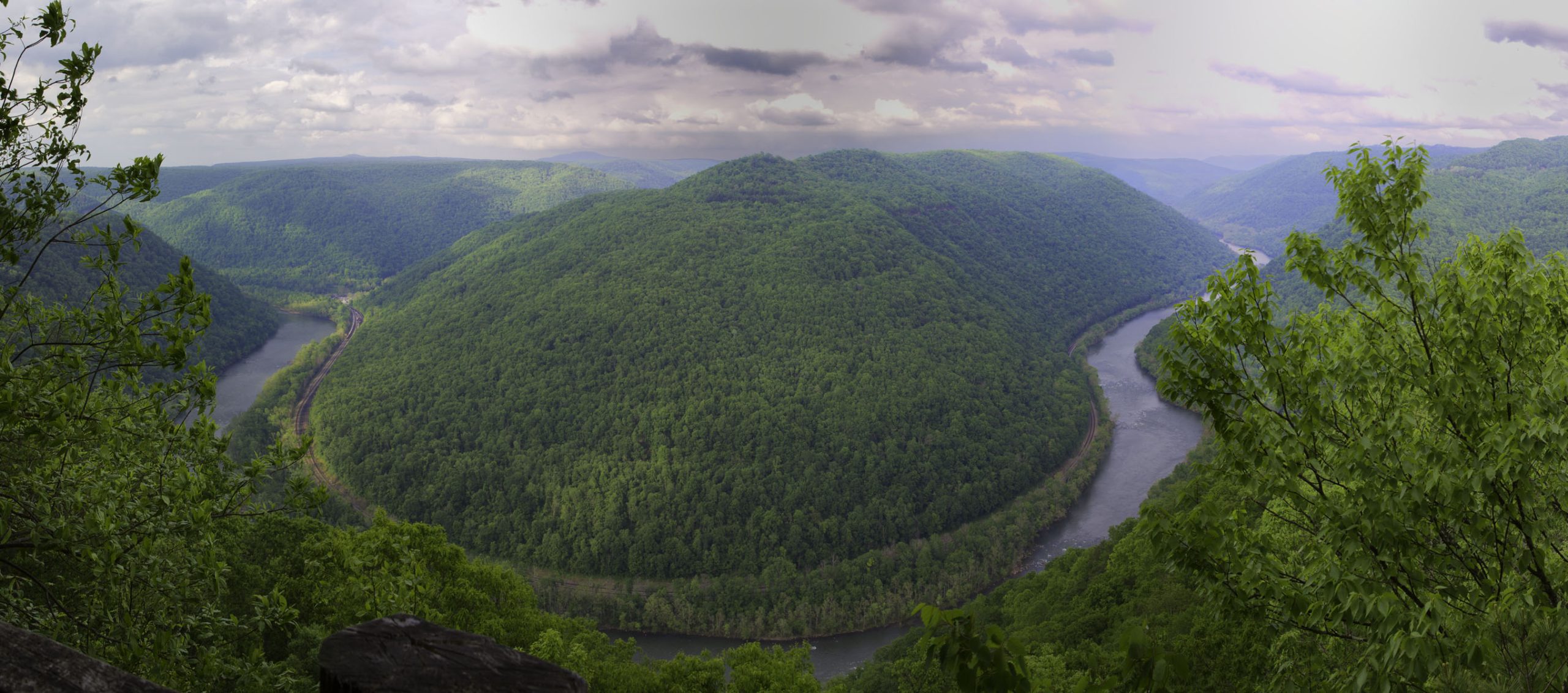 View from a rocky overlook into the New River Gorge in New River Gorge National Park & Preserve, with a winding river flanked by forested hills.