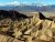 Artist's Palette in Death Valley National Park, with jagged tan ridges and distant snow-capped mountains.