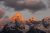 Grand Teton rises with a warm sunset glow over snow-dusted peaks in Grand Teton National Park.