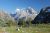 Sunlit alpine meadow at the foot of Grand Teton in Grand Teton National Park, with a small pond and rugged peaks rising behind.