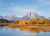 Oxbow Bend overlook in Grand Teton National Park frames the Grand Teton with autumnal orange trees and a calm reflective lake.