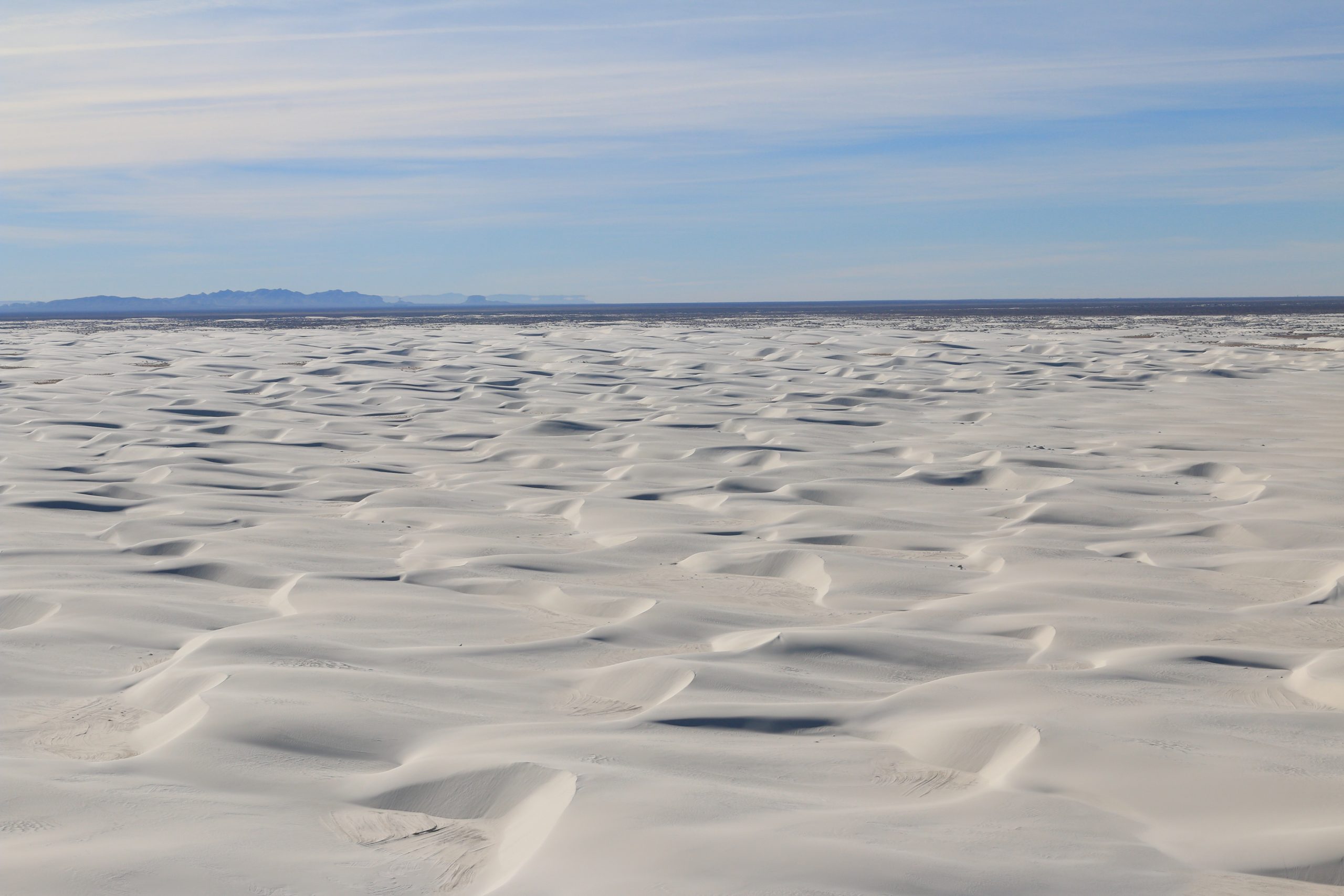 White Sands National Park gypsum dunes stretch across a bright desert landscape with distant mountains.
