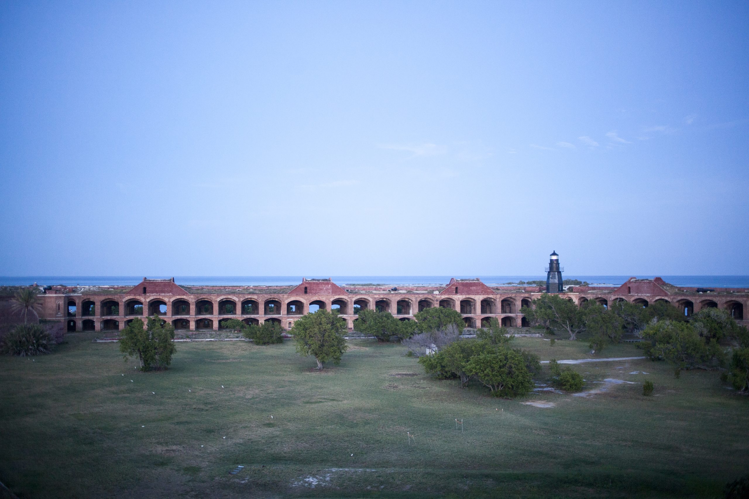 Fort Jefferson arches stretch along the brick fort at Dry Tortugas National Park, with Garden Key lighthouse in the distance.