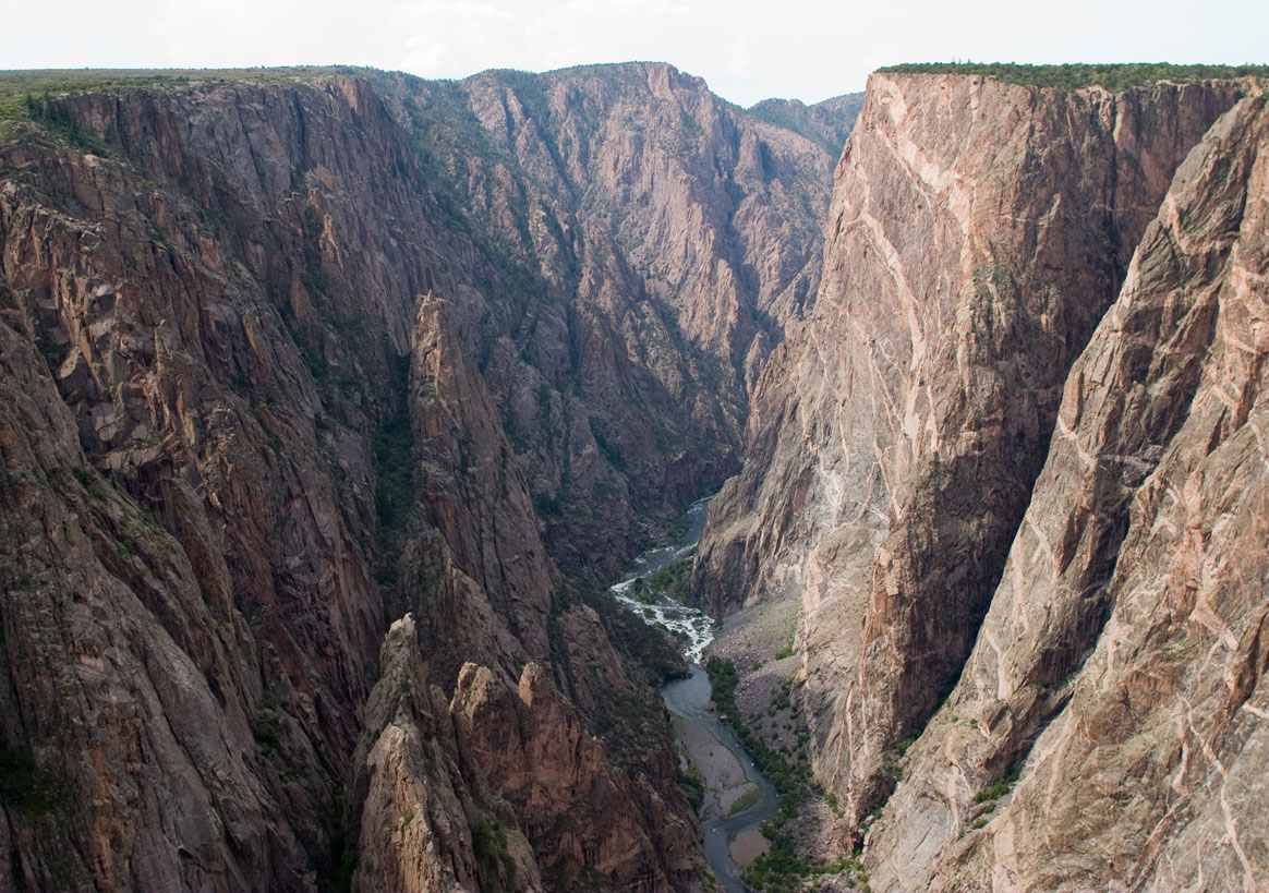 Chasm View overlook in Black Canyon Of The Gunnison National Park showing sheer canyon walls with a winding Gunnison River far below.