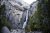Yosemite National Park — a tall waterfall drops between sheer granite cliffs in a forested canyon.