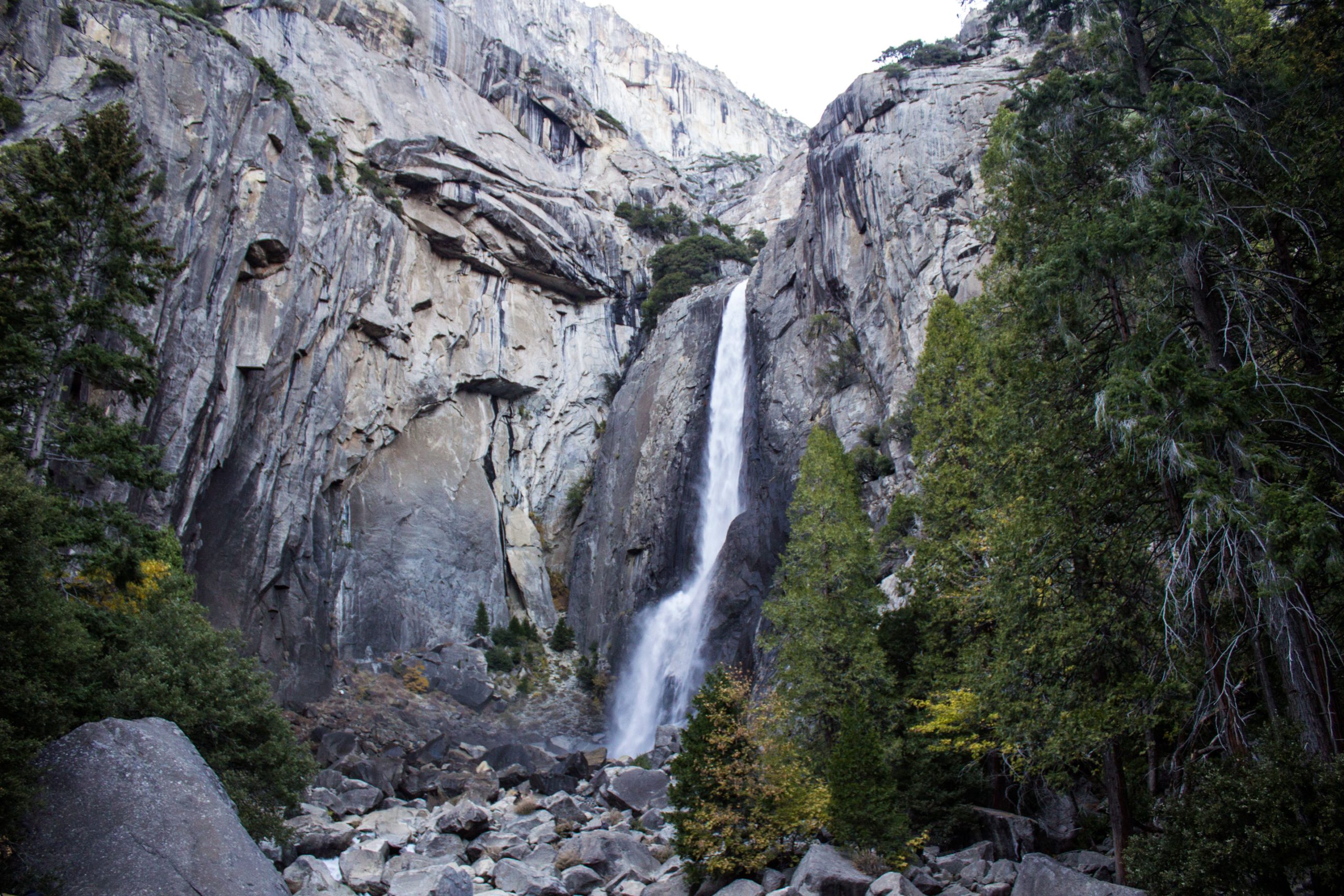 Yosemite National Park — a tall waterfall drops between sheer granite cliffs in a forested canyon.