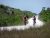 Two cyclists ride along the Shark Valley bike trail in Everglades National Park, flanked by dense mangroves and tall grasses.