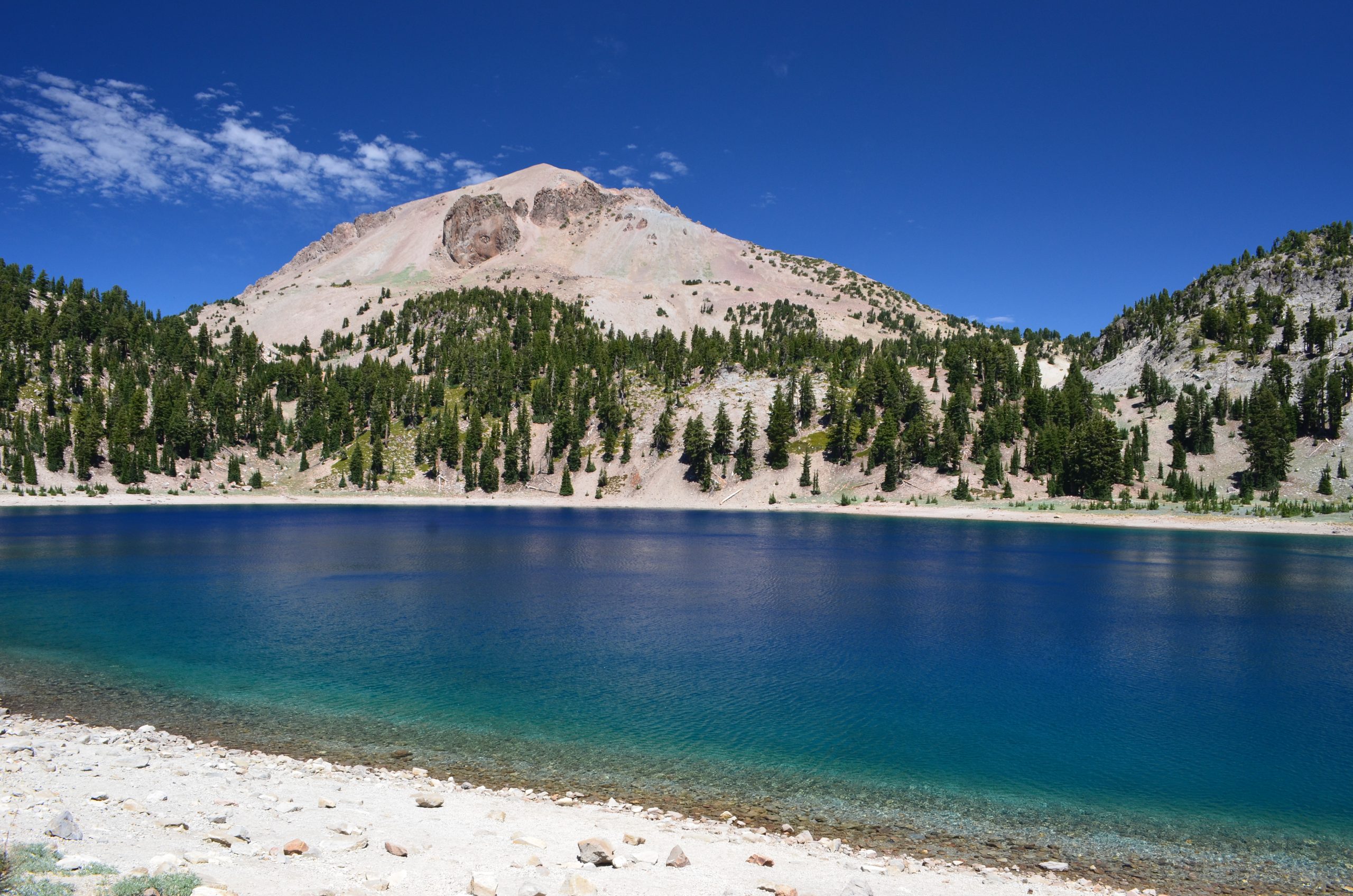 Manzanita Lake at Lassen Volcanic National Park with Lassen Peak towering above a forested shore.