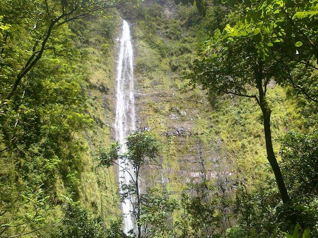 Waimoku Falls along the Pipiwai Trail in Haleakalā National Park, surrounded by lush tropical rainforest and canyon walls.