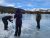 Figures drill into the frozen Bear Lake in Rocky Mountain National Park, snow-capped peaks in the background.